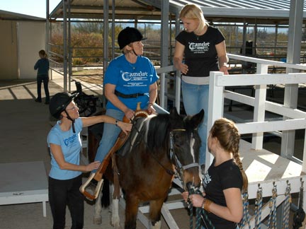 Mounted student next to ramp with instructor and volunteers