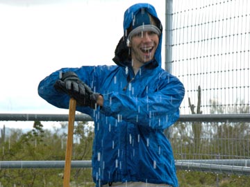 smiling young man in rain, mucking stalls