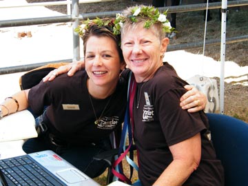 two smiling volunteers with flowered headresses hugging at Hooves & Heroes event