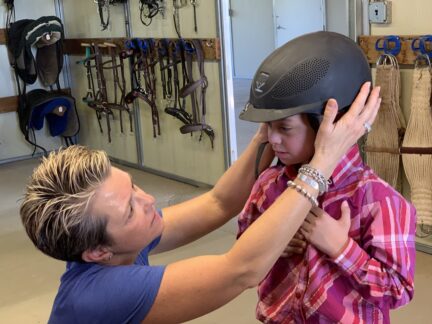 Jeanne fits a helmet on a student
