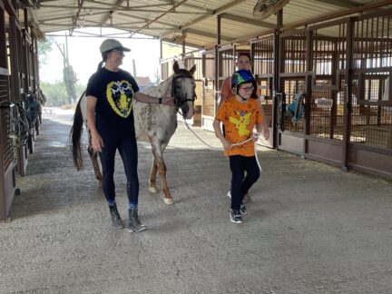 Student leading Jojo with help from a volunteer